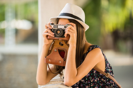 在帽子的年轻美丽的妇女正在拍摄与老式相机, 户外图片