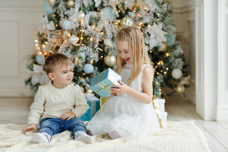 小可爱的弟弟和妹妹坐在附近一棵圣诞树