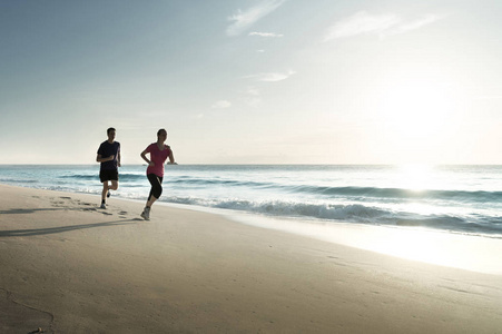 男人和女人在日落时分在地处热带的海滩上运行