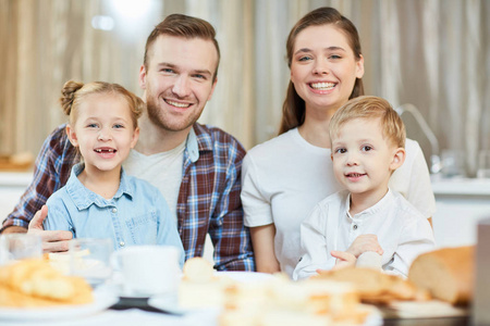 快乐的家庭四坐在服务的表, 并在家里吃早餐或晚餐