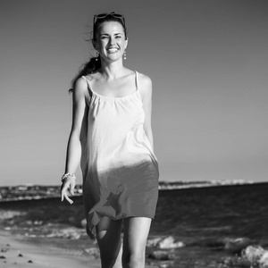 微笑健康的女人穿着在海边的夜晚散步