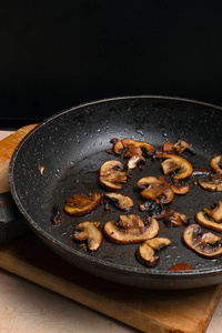 煎蘑菇在煎锅在木桌。晚餐的菜。关闭视图