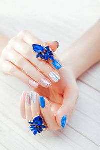 美丽的指甲与耳环。蓝色, 白色, 粉红色的组合。时尚指甲女手