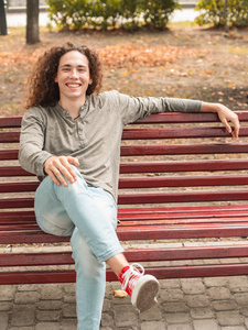 坐在公园长椅上的微笑的年轻人图片