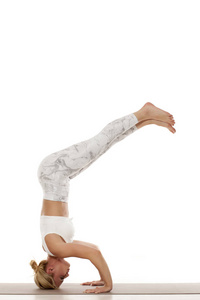三脚架倒立。Mukta 再见倒立。瑜伽, 运动, 训练和生活方式概念白色运动衫的年轻金发女郎做瑜伽练习