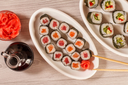 不同的寿司卷上陶瓷板, 筷子, 玻璃 bottl