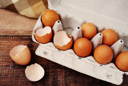 鸡蛋和打破的鸡蛋在一个纸板托盘木台面上的贝壳