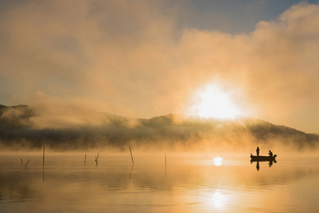 日出时分湖河口湖，人们在一条船，silhoue 捕鱼