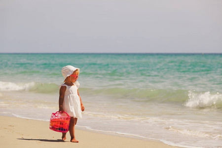 玩具的小女孩走在沙滩上