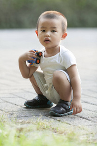 可爱的中国娃娃男孩玩玩具车在公园里