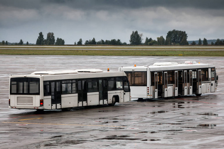 在雨天, 机场停机坪上有两辆空班车。