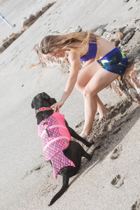 漂亮的年轻女子与她的狗穿着潜水衣在游泳