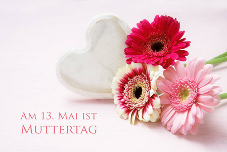 粉红色的花朵和白色彩绘木心在一个粉彩色的背景, 德国文字是13。Muttertag, 意思是5月13日是母亲节