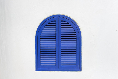 蓝色的木制窗口关闭与木制的百叶窗，粉刷成白色的墙上
