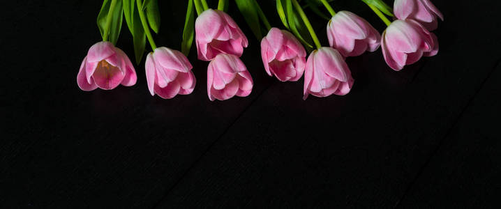 黑色木质背景明亮的粉红色郁金香花的边界