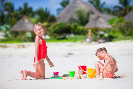 可爱的小女孩，在暑假期间。孩子们在白色的沙滩上玩沙滩玩具