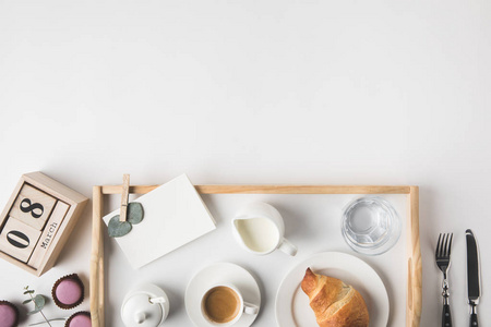 平躺与杯咖啡和牛角包早餐托盘上的白色桌面