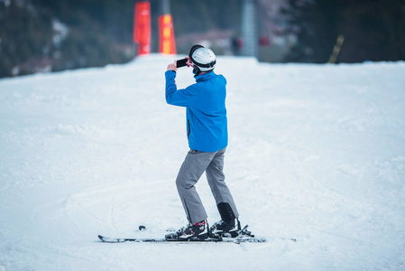 男滑雪者用智能手机拍照