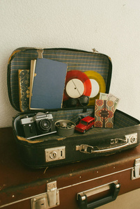 打开皮革旅行 valises 或旧手提箱与照相机, 玩具汽车, 老式乙烯基记录, 护照, 金钱, 太阳镜并且老书关闭, 旅行相片