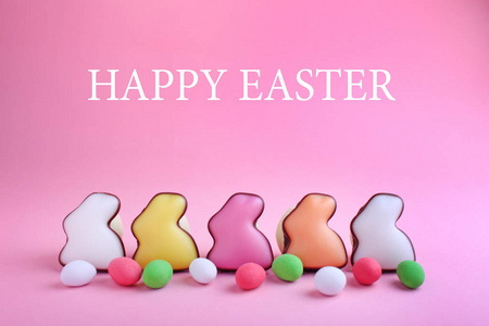 彩釉饼干形状的兔子糖果和字母粉红色背景快乐复活节
