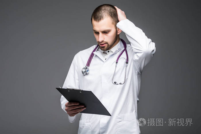 灰色背景下的困惑年轻英俊男子医生持有空白孤立的肖像