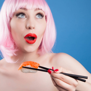 红红的嘴唇和吃寿司特写的粉红头发的漂亮女孩