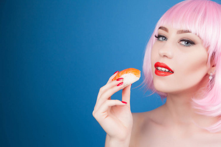 红红的嘴唇和吃寿司特写的粉红头发的漂亮女孩