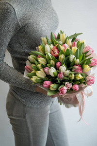 女性抱住美丽花束的彩色春季郁金香花