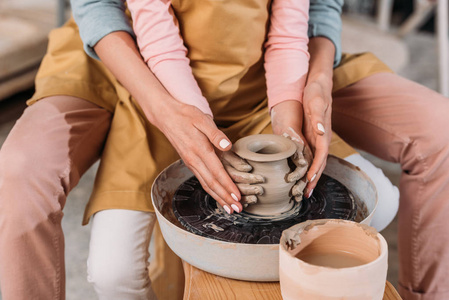在陶轮上制作陶瓷壶的老师和孩子的裁剪视图