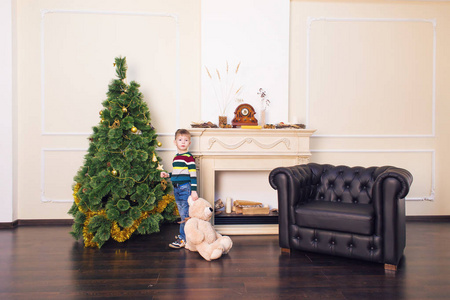 儿童男孩玩毛绒玩具熊附近圣诞树