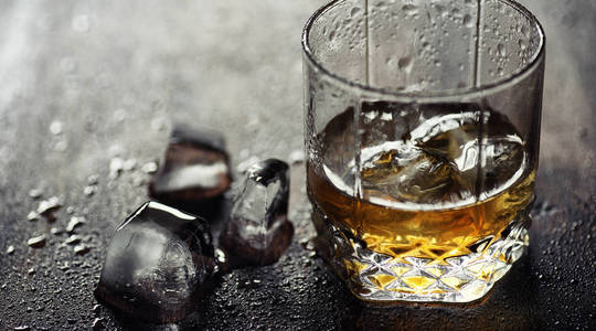 威士忌加冰块和玻璃杯木桌上的冰块