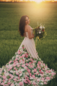 年轻的新娘穿着裙子从鲜花走在草地上, 微笑着