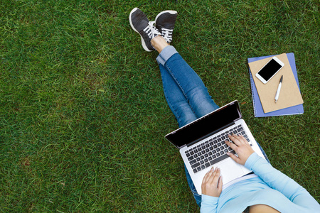 女学生坐在公园与笔记本电脑的顶级视图