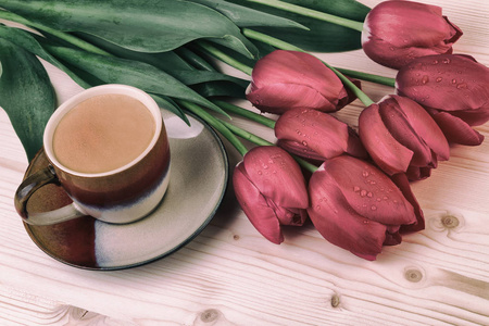 红色郁金香木桌上的咖啡一杯。复古风格的咖啡