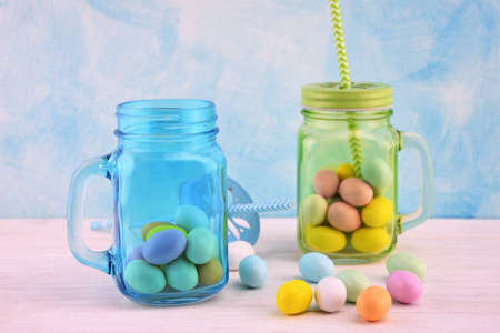 带彩色复活节彩蛋的蓝绿色透明玻璃罐