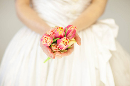 女新娘手捧着春天的花朵郁金香和玫瑰, 感官工作室拍摄可作为背景