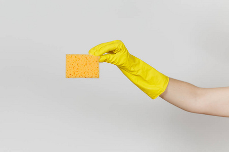 女性手的特写在黄色手套水平举行黄色橙色海绵清洗和洗涤盘子被隔绝在白色背景。清洁用品的概念。复制广告空间