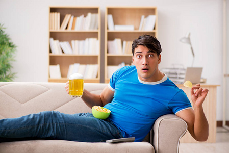 男人看足球在家里坐在沙发上