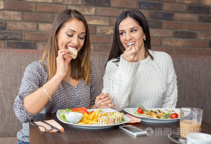 两个女朋友一起吃午饭在餐馆互相看着对方