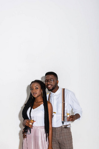 时尚年轻的非洲裔美国人夫妇持有香槟和微笑的白色相机