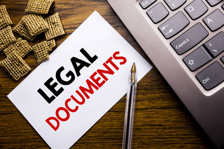 手写公告文本, 显示法律文档。在笔记本电脑键盘旁边的木质背景上用粘纸书写的合同文件的业务概念