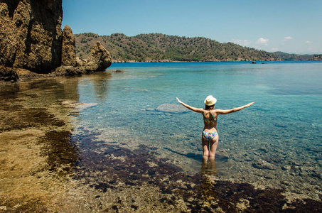 年轻的微笑的女人漂亮的运动苗条的身影在 swimsuite 做瑜伽自由运动站在蓝水绿松石礁湖观岛岩石海岸夏季健康假期