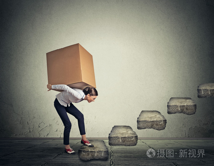 困难的任务概念年轻女子背着沉重的箱子上楼
