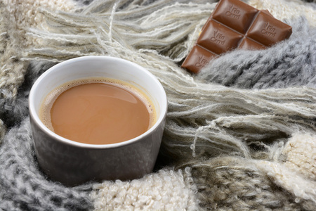 咖啡杯与灰色 象牙 本色的针织围巾围在它和巧克力热巧克力