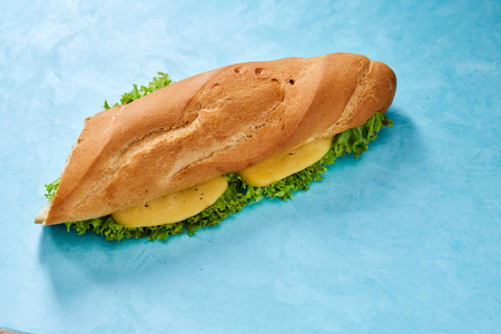 新鲜和美味的三明治与奶酪和蔬菜在切割板上蓝色背景, 选择性聚焦