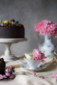 复活节的巧克力蛋糕, 花瓶里有花。节日餐桌装饰用复活节蛋糕, 鲜花和五颜六色的鸡蛋