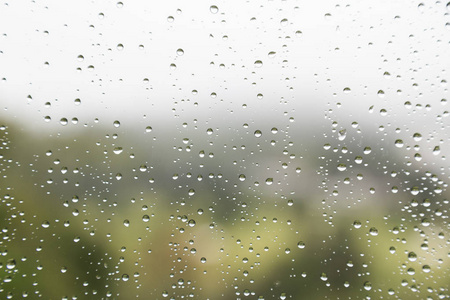 雨水滴在玻璃窗口与景区绿化视图