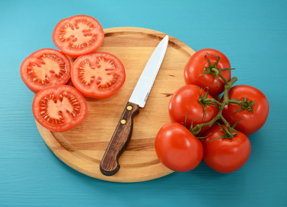 西红柿，整个和切片刀在木板上