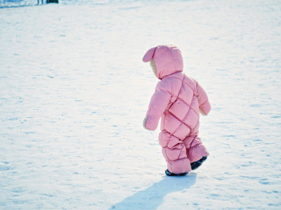 一岁的小女孩呈现冬季公园的第一步
