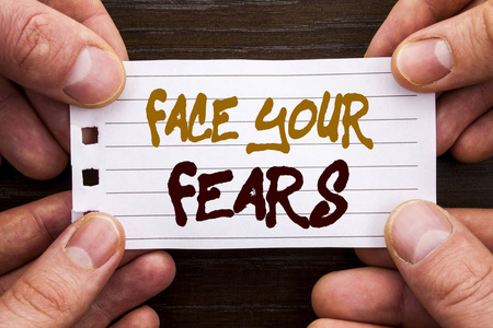 手写的文字符号显示你的恐惧。企业理念为挑战恐惧 Fourage 信心勇敢的勇气写在粘纸条上手拿着手指